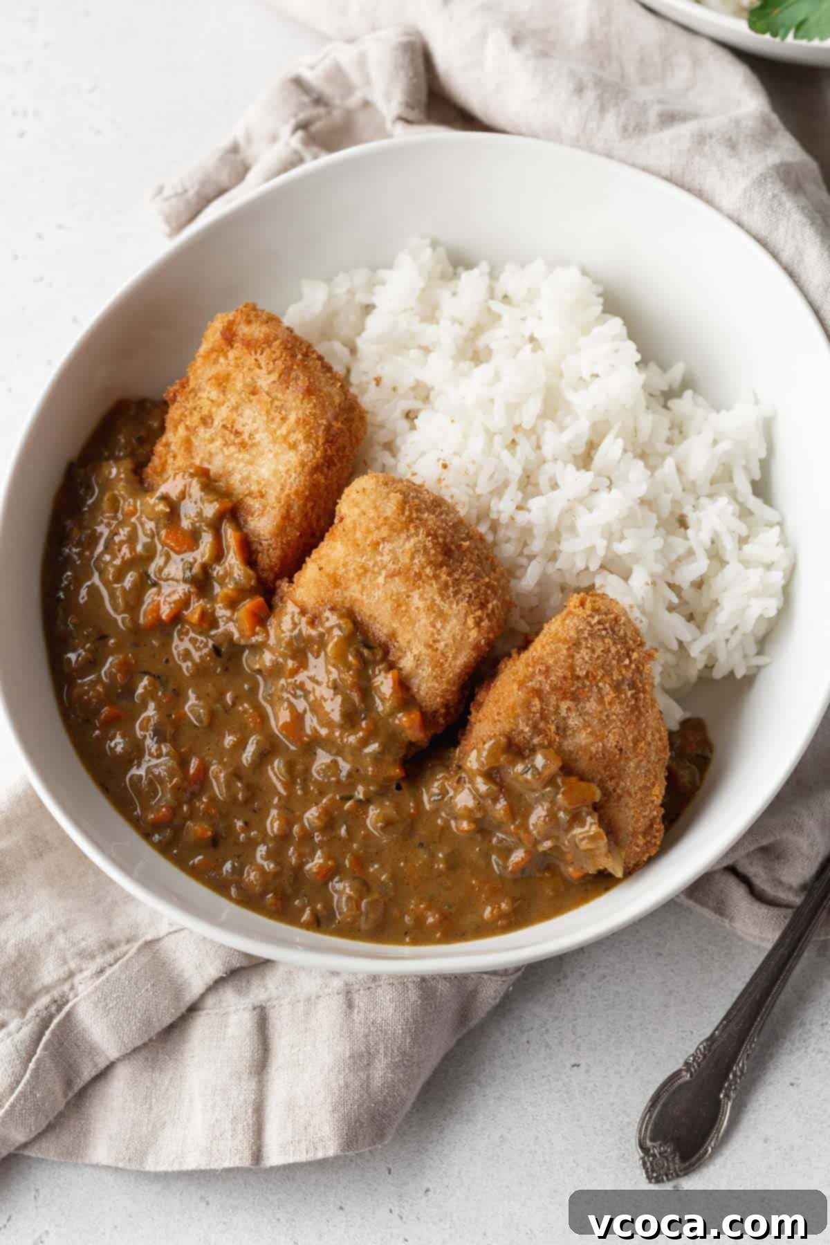 A bowl of white rice topped with katsu and vegan curry.