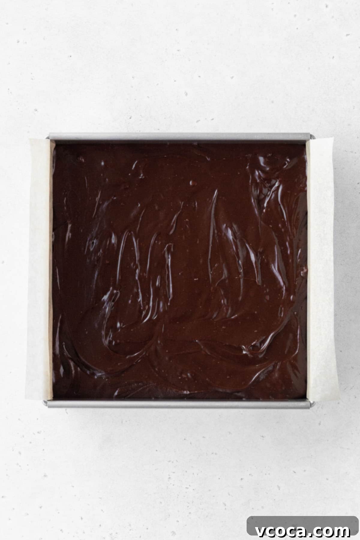 Plant-Based Fudge 7 Dairy-free fudge batter poured into the parchment-lined baking tin and smoothed out with a spatula.