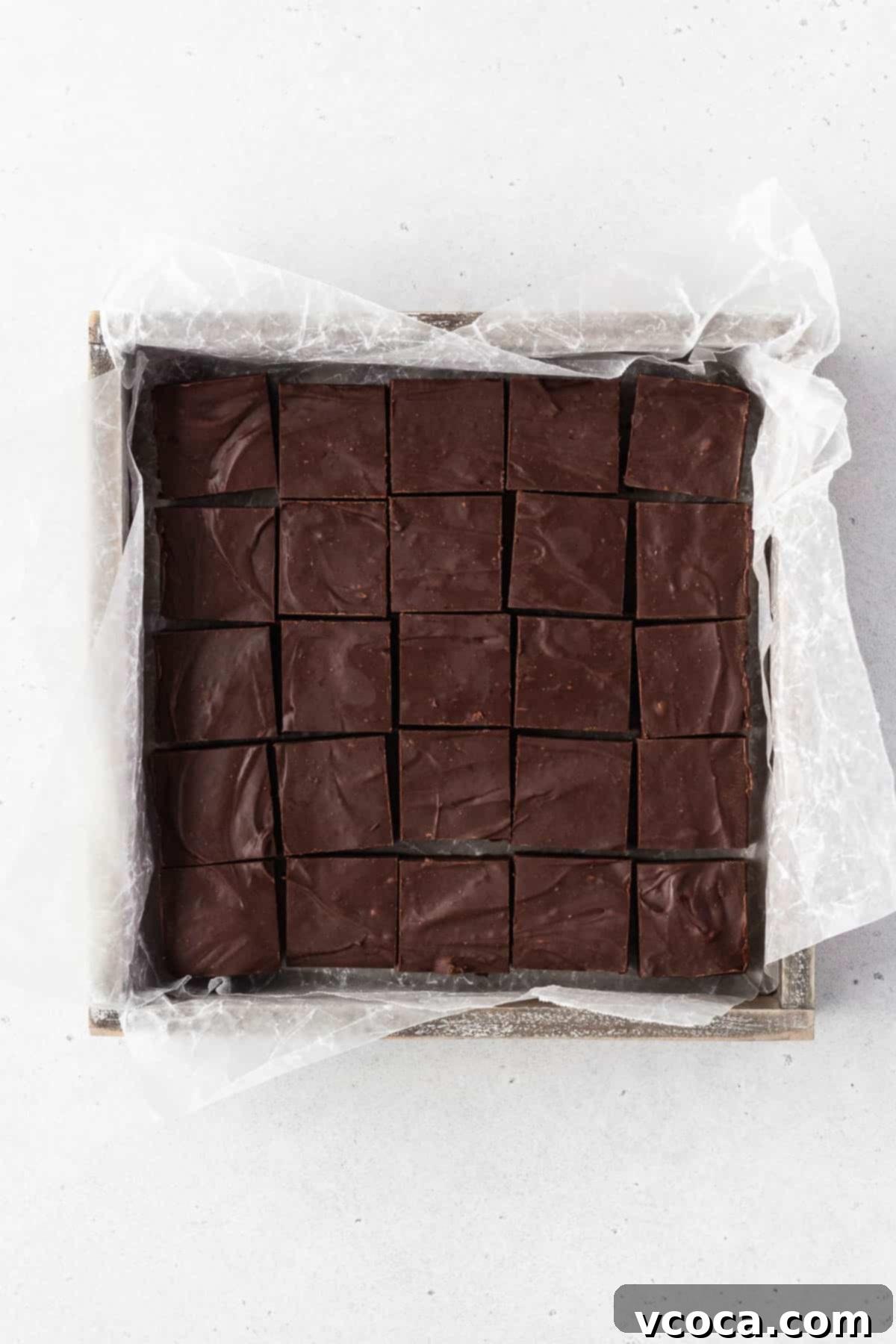 Plant-Based Fudge 8 Finished batch of dairy-free vegan fudge in a wooden box with parchment paper after being cut into squares.