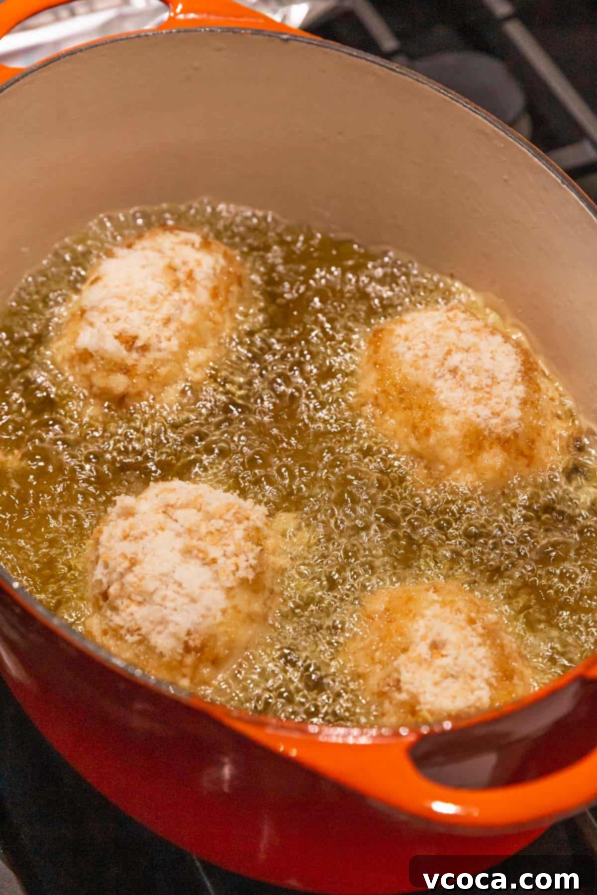 Plant-Powered Potato Croquettes 15 4 vegan potato croquettes frying in an orange enameled cast iron dutch oven. The bubbles are vigorous.