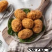 Plant-Powered Potato Croquettes 19 Vegan curry potato croquettes on a serving platter atop a wooden cutting board.