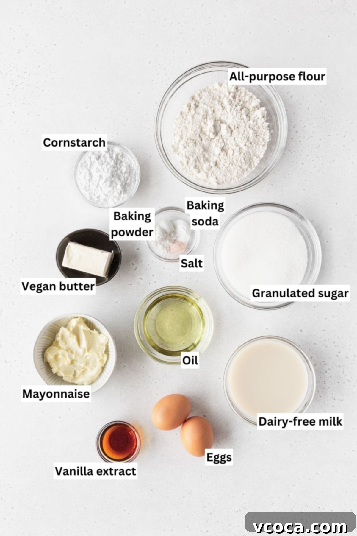 Ingredients for making dairy-free vanilla cupcakes laid out on a white table.