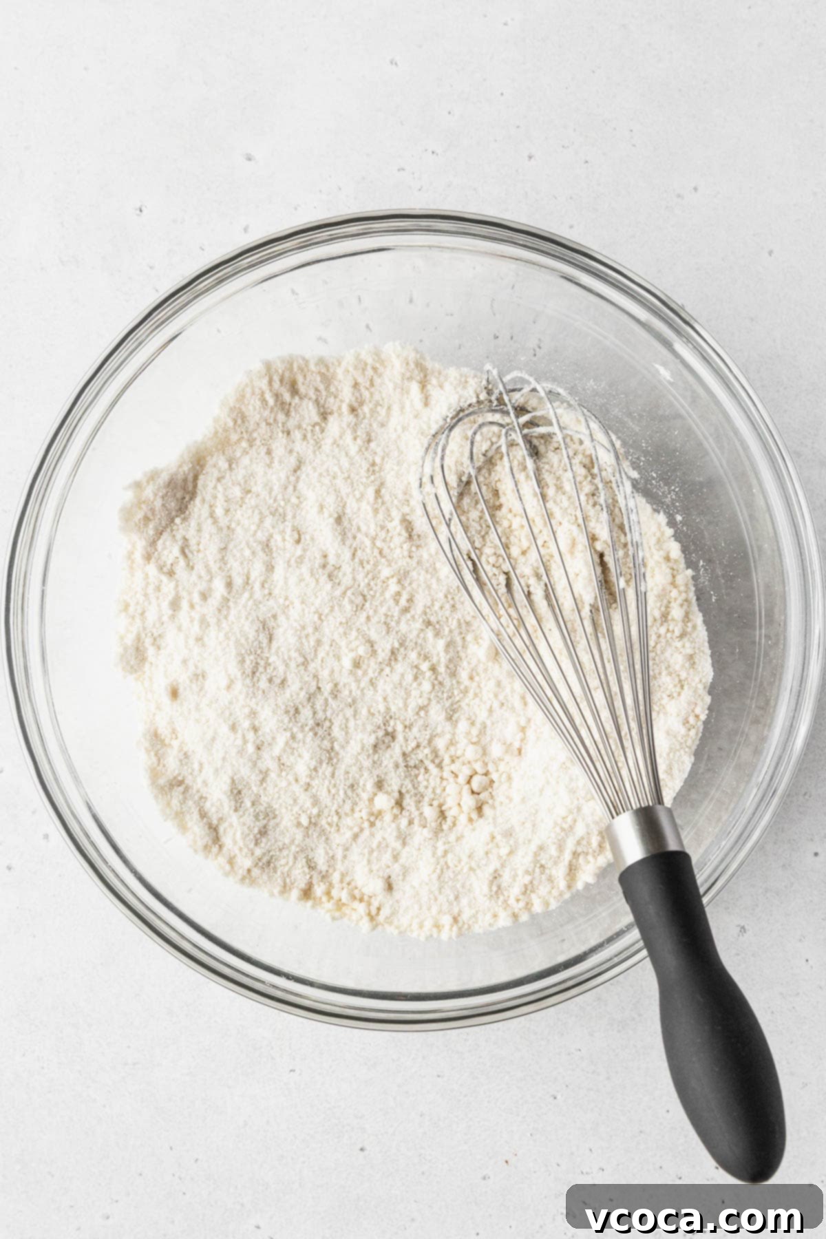 Dry ingredients whisked together in a clear glass mixing bowl.