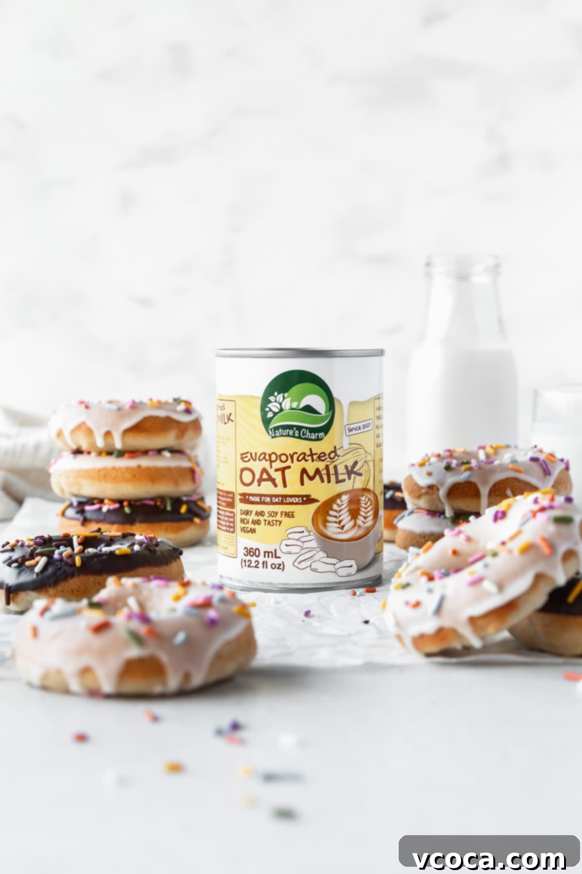 Wholesome Plant-Based Baked Donuts 12 Can of Nature's Charm evaporated oat milk in the center of a table with vegan dairy-free donuts all around.