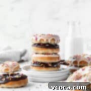 Wholesome Plant-Based Baked Donuts 14 Stack of alternating chocolate and vanilla glazed baked vegan donuts on a stack of white dessert plates with a jug of non-dairy milk in the background.
