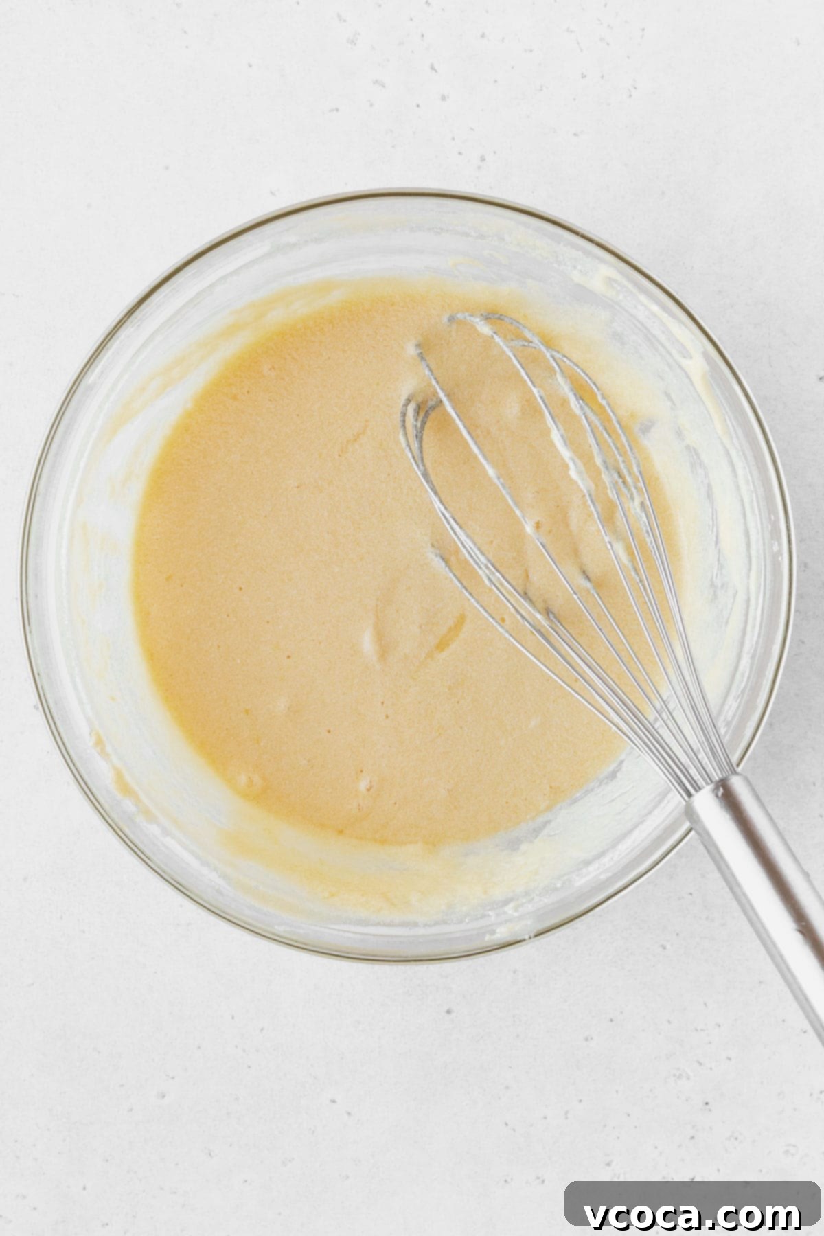 Luscious Lemon Curd Cake 8 Lemon curd ingredients mixed together in a glass bowl with a whisk.