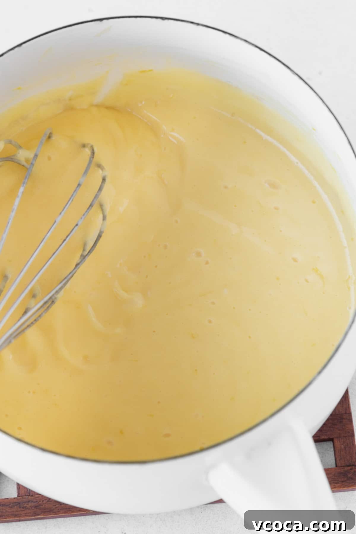 Luscious Lemon Curd Cake 9 Cooking the dairy-free lemon curd in a white saucepan.