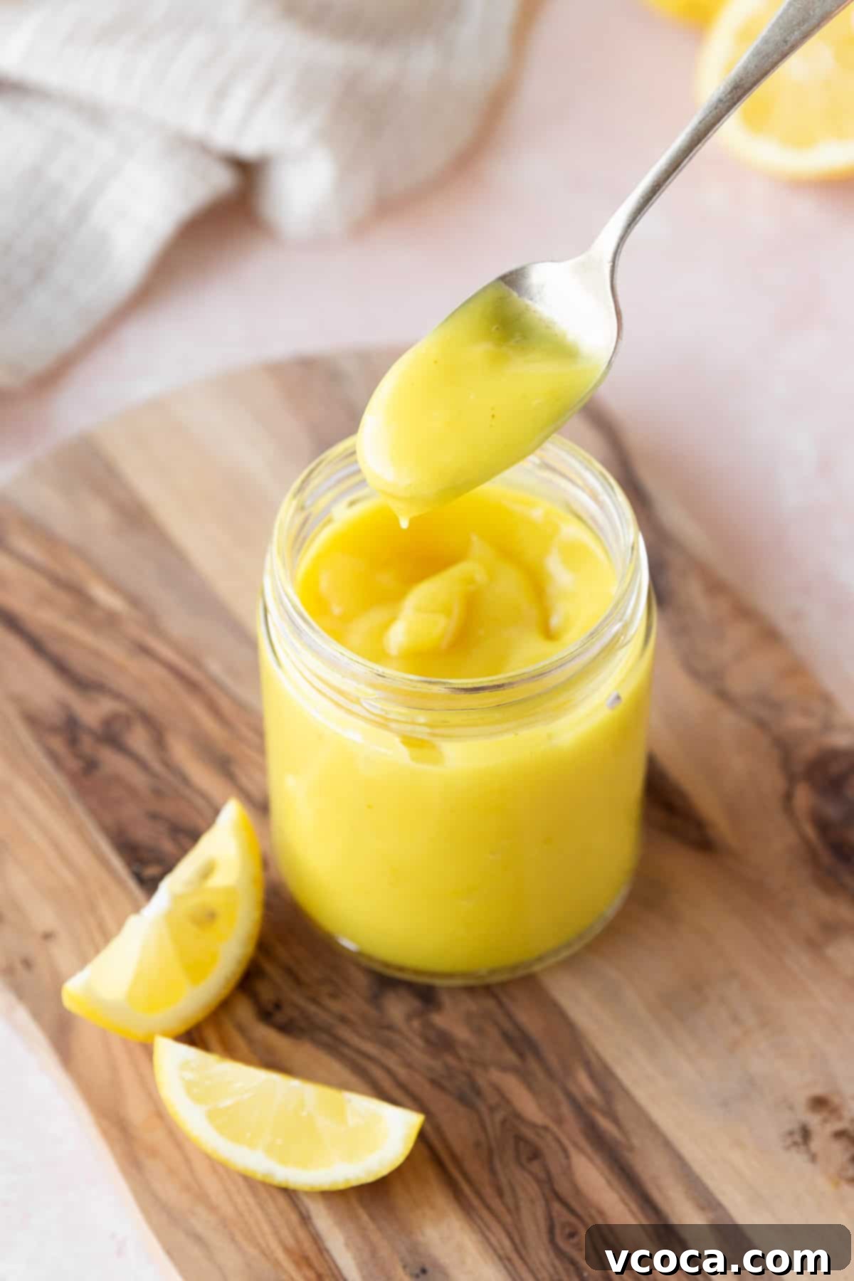 45 degree angle shot of a spoonful of vegan lemon curd above the mason jar to show the thick consistency of the homemade lemon curd.