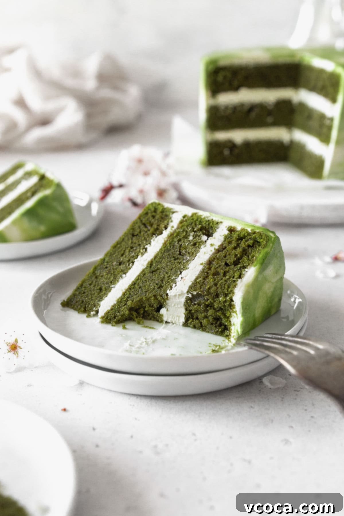 Heavenly Matcha Cake 14 An up-close shot of a piece of matcha cake on a dessert plate with a bite taken out of it, revealing the perfect layers and rich green color.