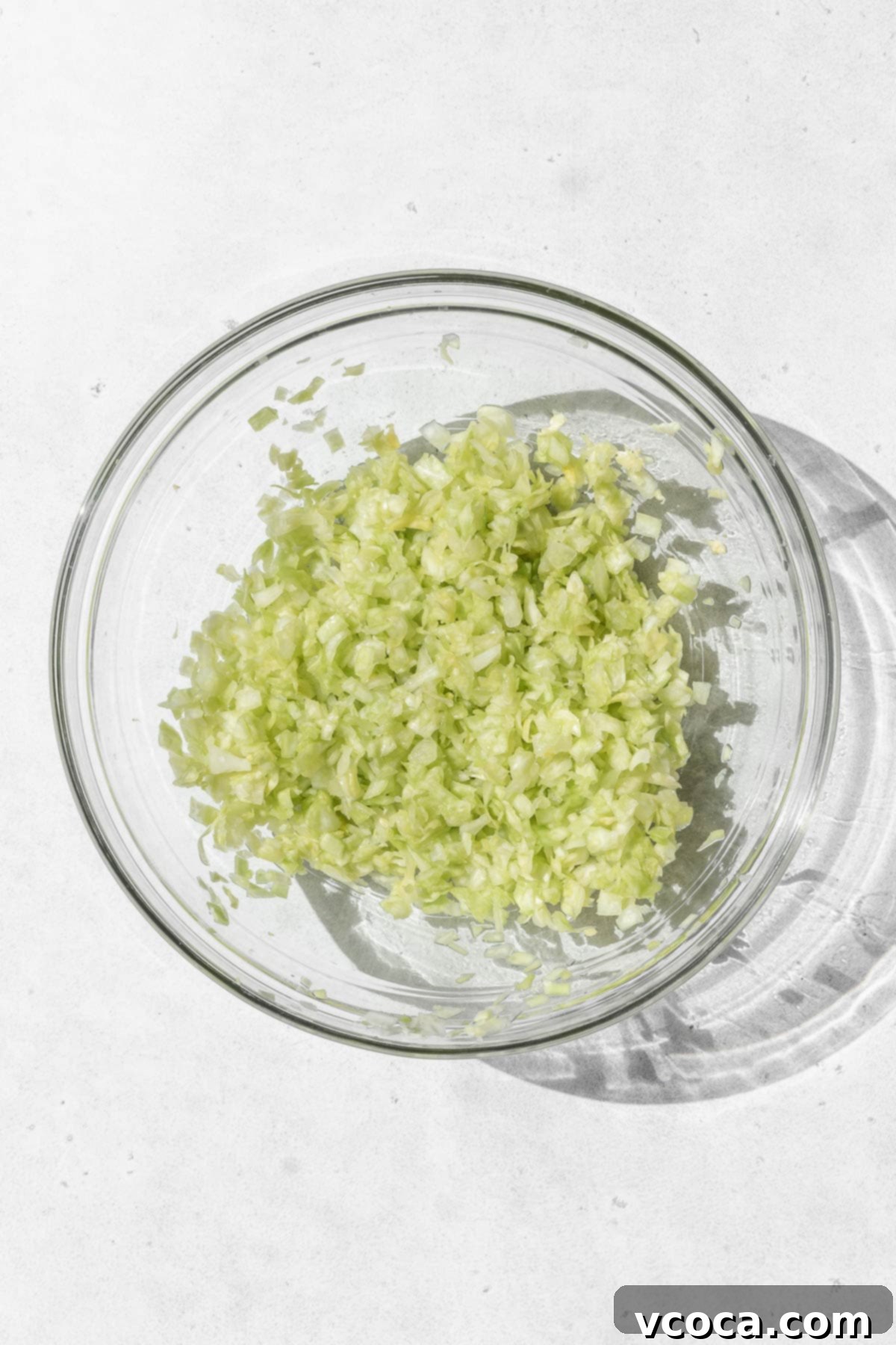 Plant-Based Vegetable Gyoza 5 Minced cabbage in a glass bowl on a white surface.