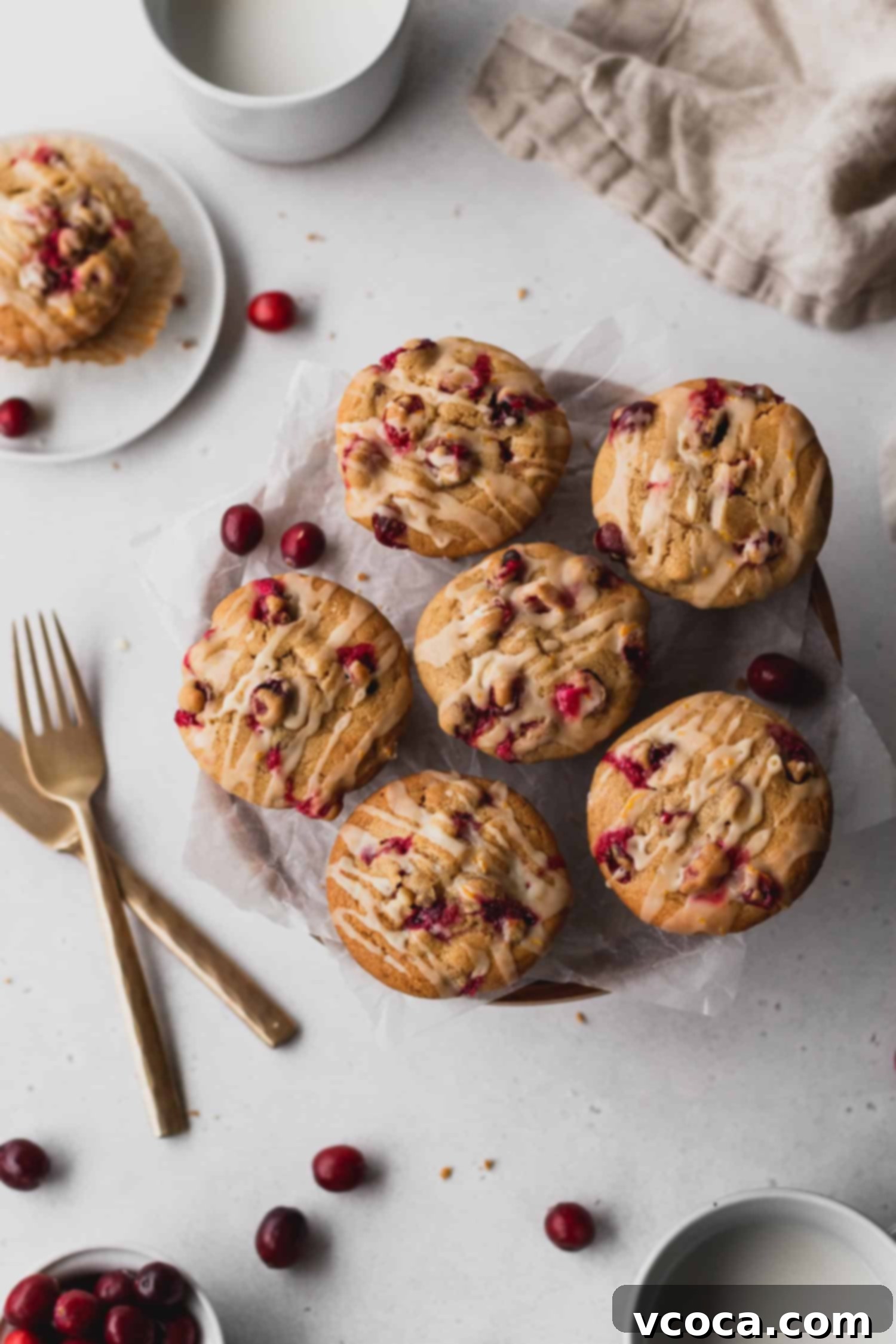 Zesty Orange Cranberry Muffins 3 Two perfectly baked cranberry orange muffins generously drizzled with a sweet and tangy orange icing, ready for serving.
