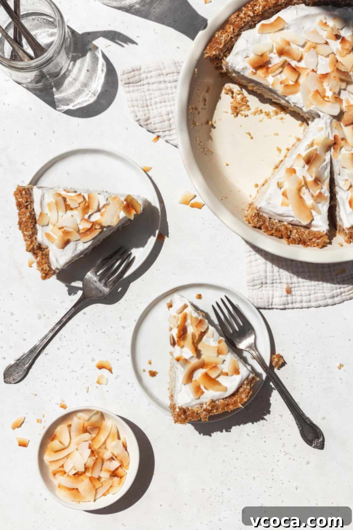 Divine Vegan Coconut Cream Pie Gluten Free 2 Overhead shot of two dessert plates each with a slice of creamy vegan coconut cream pie topped with toasted coconut flakes.