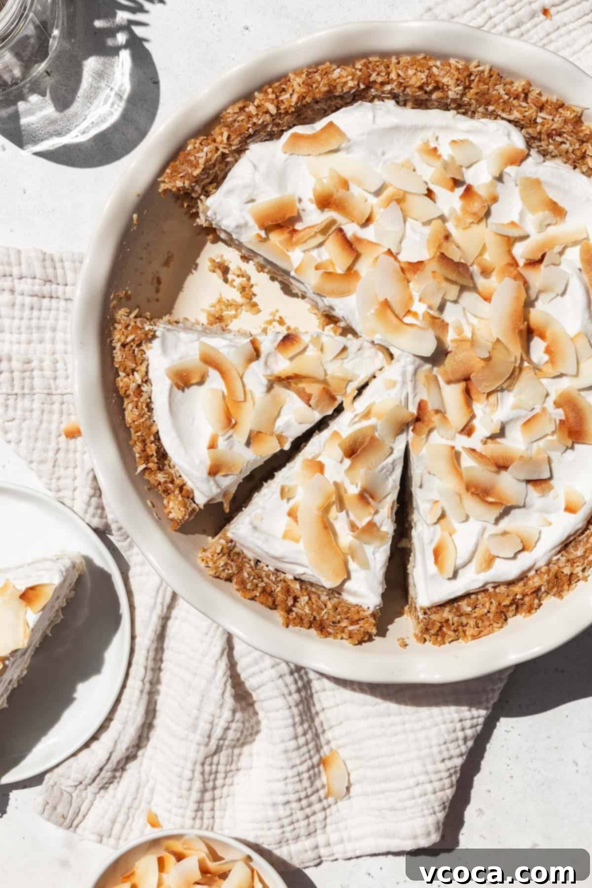 Divine Vegan Coconut Cream Pie Gluten Free 15 Overhead shot of vegan gluten-free coconut cream pie in a pie dish with two slices prepped to serve.