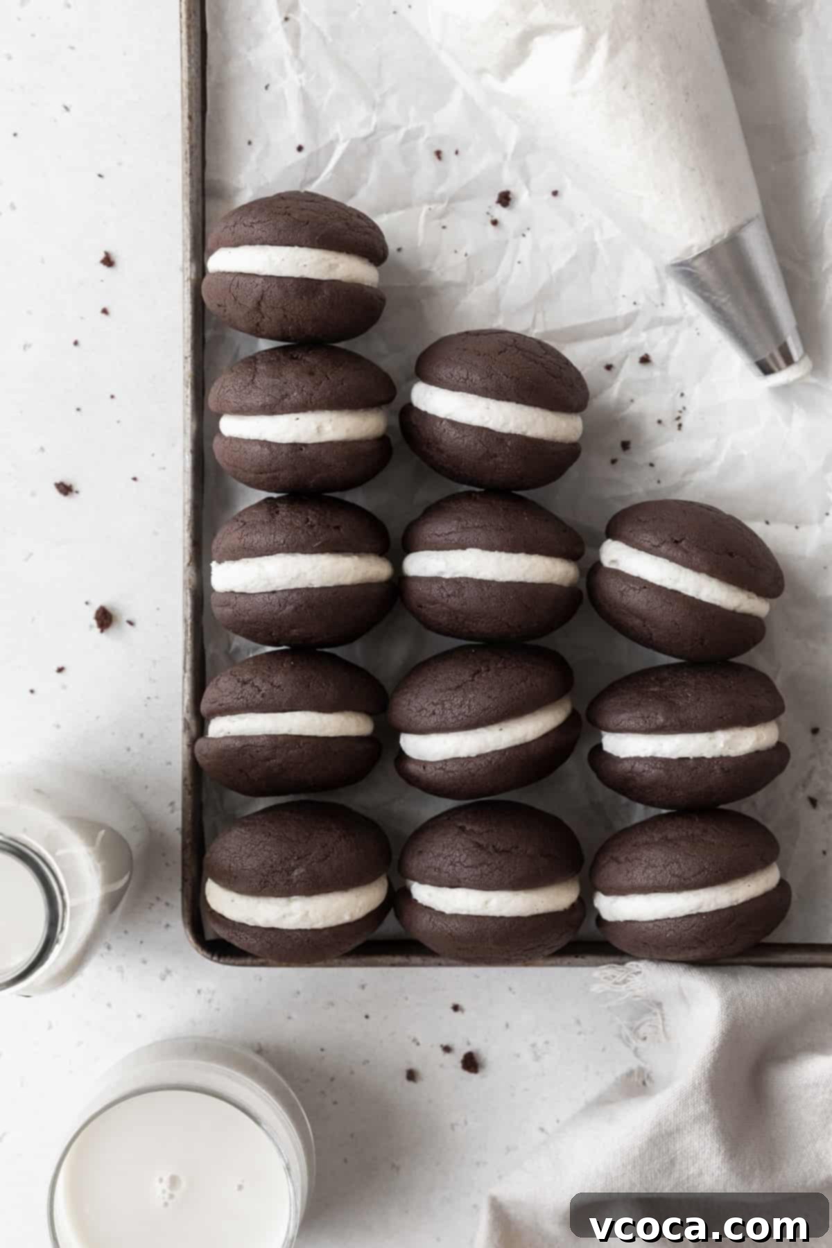 Gluten-Free Whoopie Pies 3 A parchment paper lined baking tray with gluten-free whoopie pies and a piping bag.
