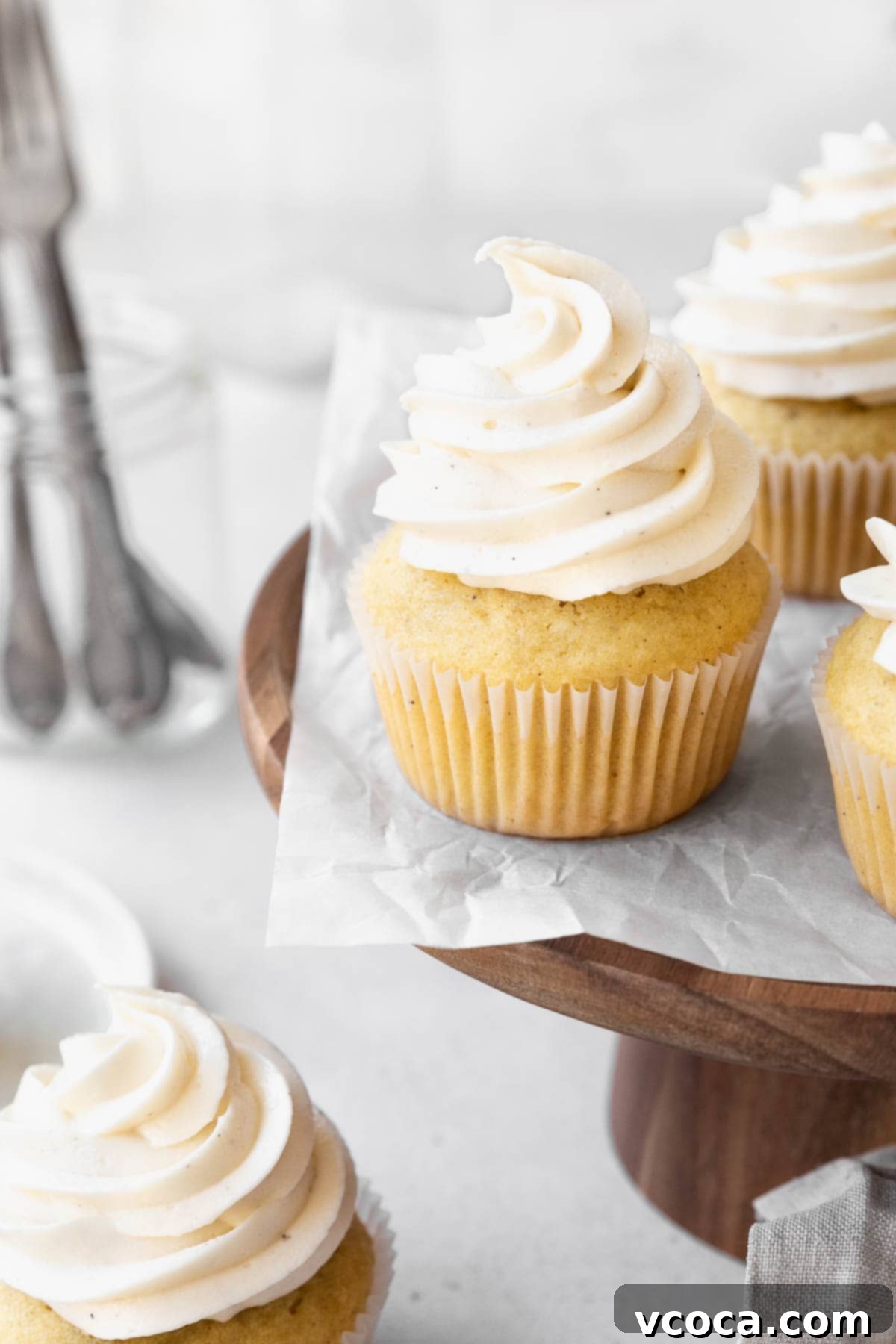 Velvety Vegan Buttercream 3 Wooden cake stand with dairy-free buttercream topped vanilla cupcakes.