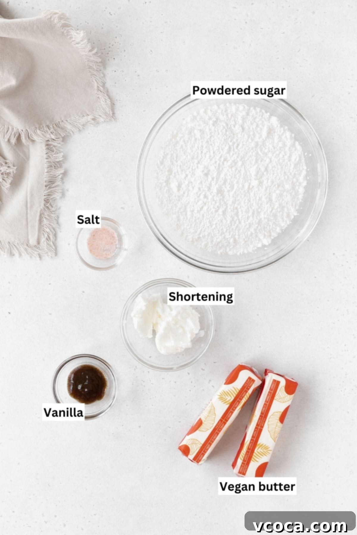 Velvety Vegan Buttercream 4 Ingredients needed to make dairy-free buttercream frosting laid out on a white table with text overlay.