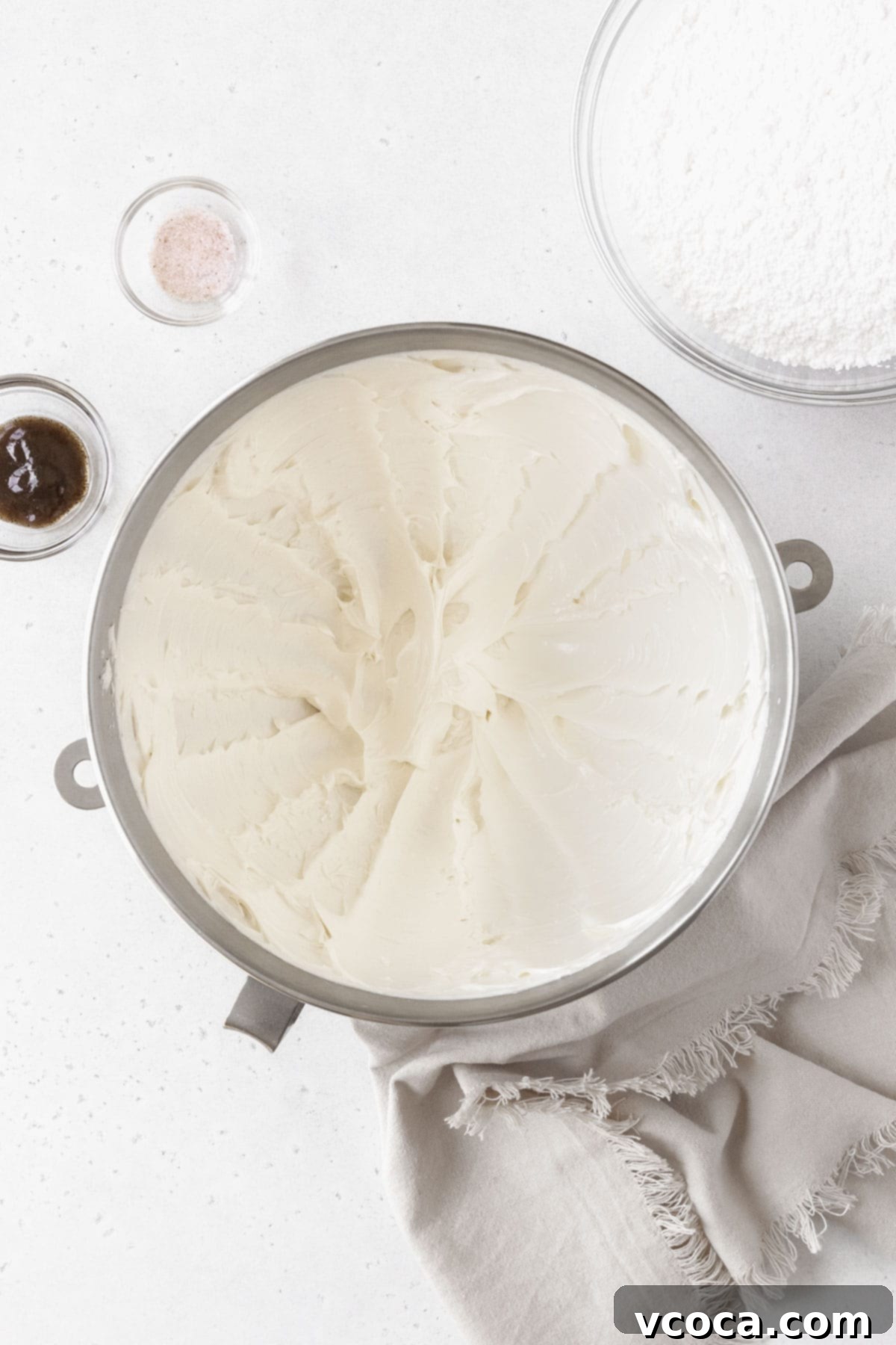 Velvety Vegan Buttercream 5 A silver mixing bowl of whipped butter next to a bowl of powdered sugar and vanilla.