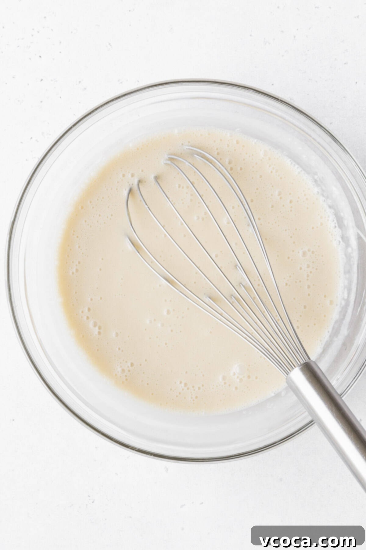 The perfectly blended gluten-free and dairy-free tres leches milk soak, creating a smooth and luscious mixture in a clear glass mixing bowl, poised to transform the cake into a moist masterpiece.