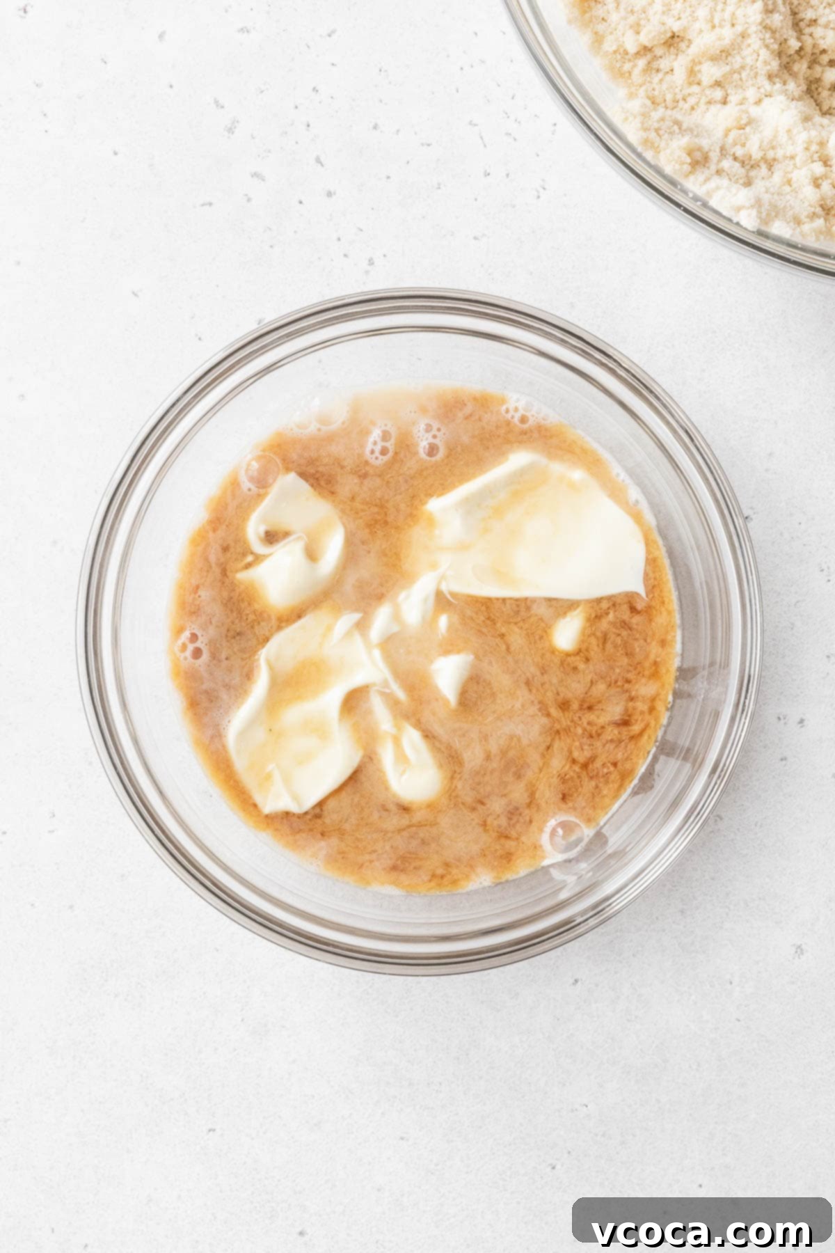 A glass mixing bowl holds a perfectly combined mixture of non-dairy milk, fragrant vanilla extract, and creamy mayonnaise, ready to be incorporated into the cake batter for a delicious gluten-free and dairy-free tres leches cake.