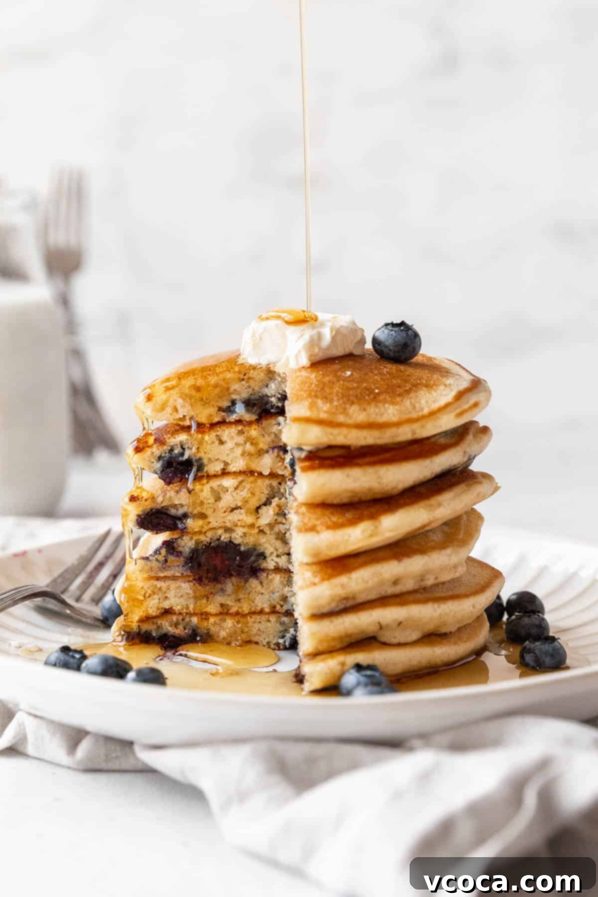 Side-on shot of a stack of muffin mix blueberry pancakes with a quarter of the tower removed to show the fluffy interior.