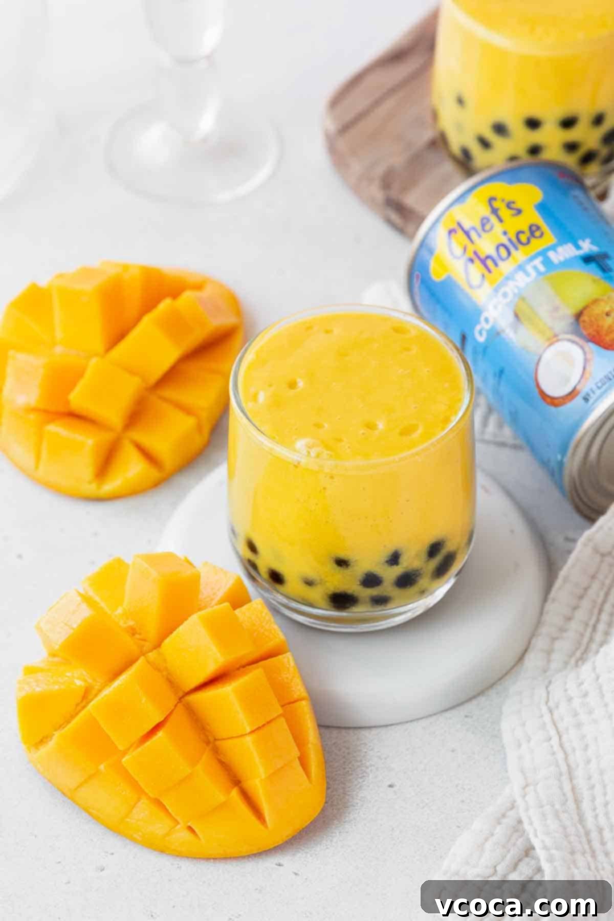 Tropical Mango Boba 13 A small glass of the mango boba tea next to a can of chef's choice coconut milk and a cubed mango.