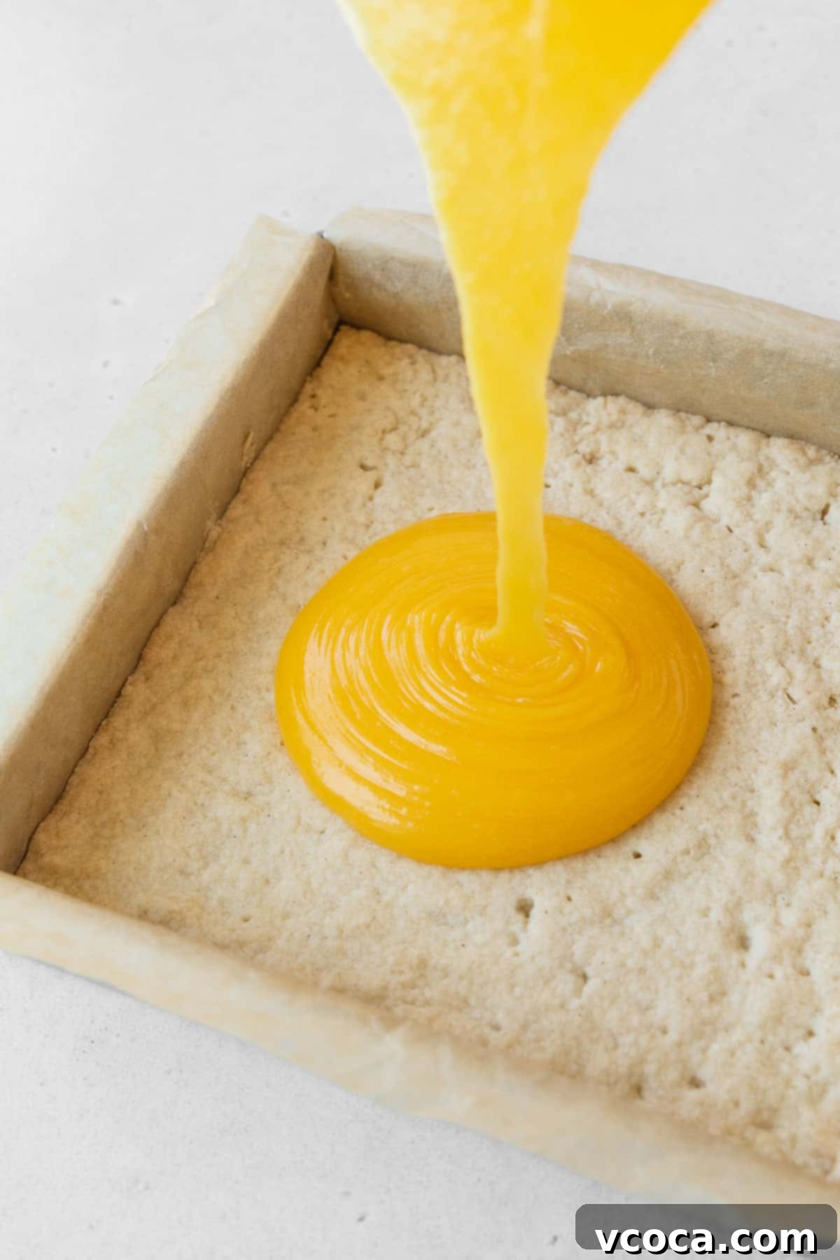 Bright and Zesty Dairy Free Lemon Bars 18 Pouring the dairy-free lemon curd filling onto the baked shortbread crust in a pan.
