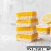 Bright and Zesty Dairy Free Lemon Bars 23 Stacked dairy-free lemon bars on the counter with powdered sugar and crumbs.