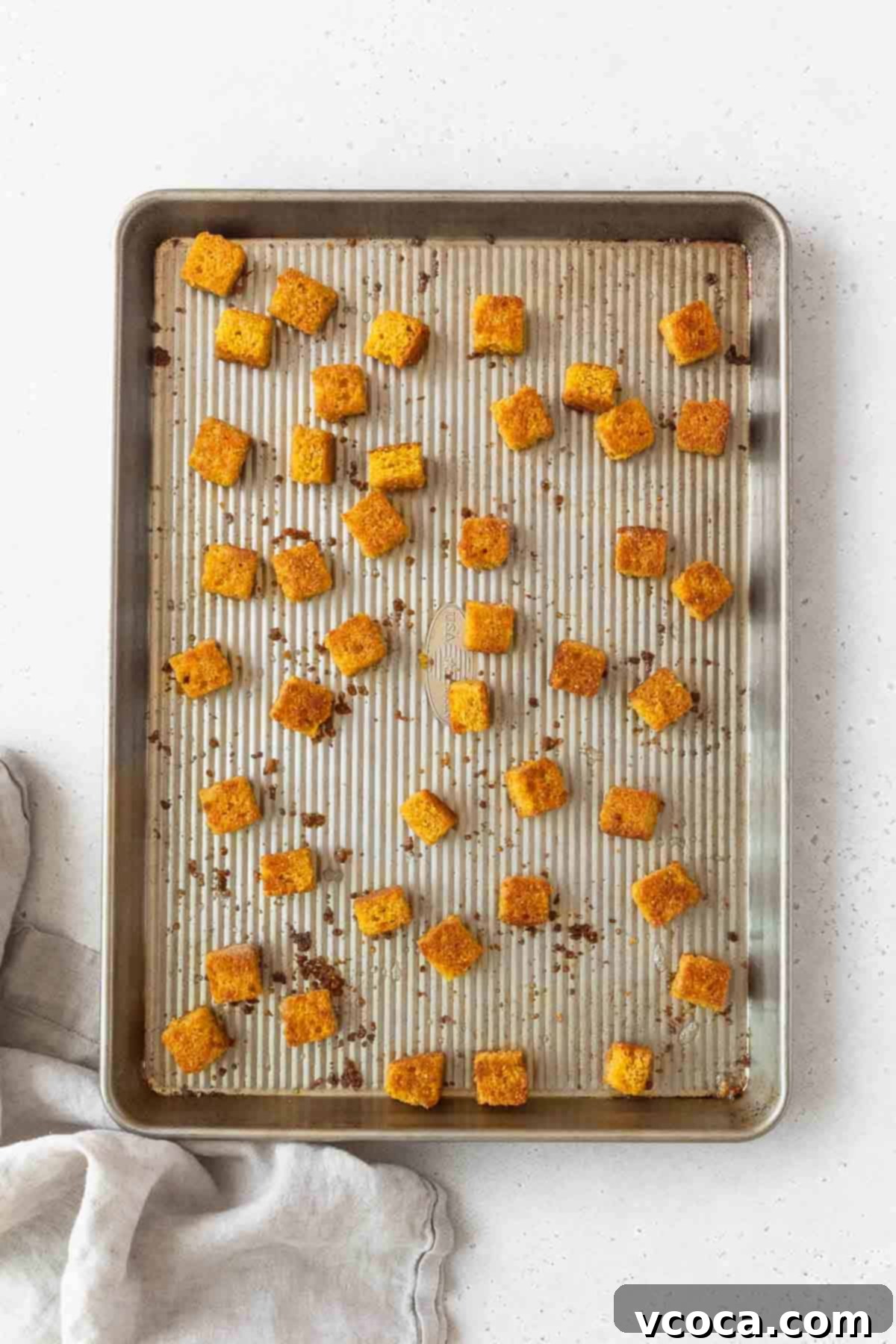 Toasted cornbread croutons on a baking sheet.