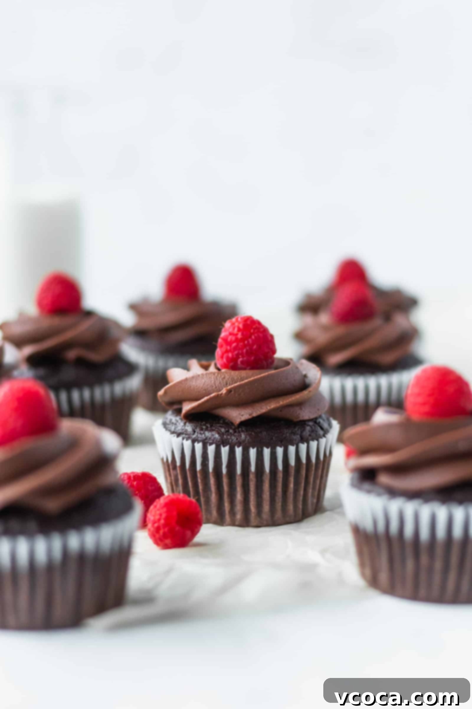 Decadent Vegan Chocolate Banana Cupcakes 7 A charming stack of delightful vegan chocolate banana cupcakes with creamy frosting, elegantly garnished with fresh raspberries.