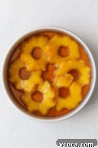 A cake pan of the brown sugar butter and pineapple rings in it.