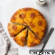 Flourless Pineapple Upside Down Delight 5 A sliced gluten-free pineapple cake on a white surface with a linen and a knife.