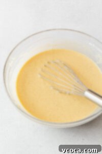 A whisked bowl of the gluten-free pineapple cake batter with a whisk in it.