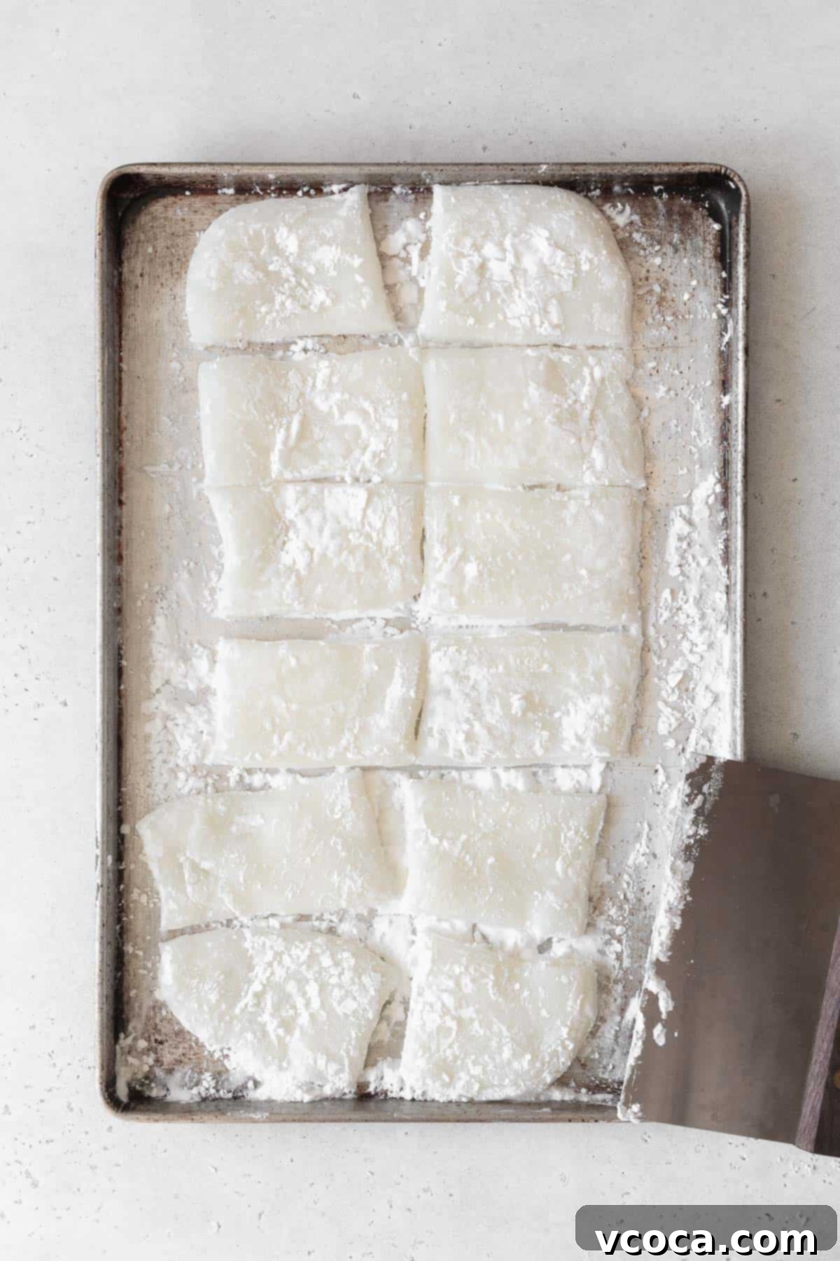 The mochi dough precisely cut into 12 even pieces using a bench scraper, demonstrating careful portioning for consistent daifuku.