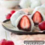A sliced strawberry mochi on a black plate.