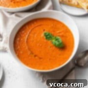 Heartwarming Roasted Tomato Soup 13 A bowl of vegan tomato soup with a drizzle of olive oil and a sprig of basil.