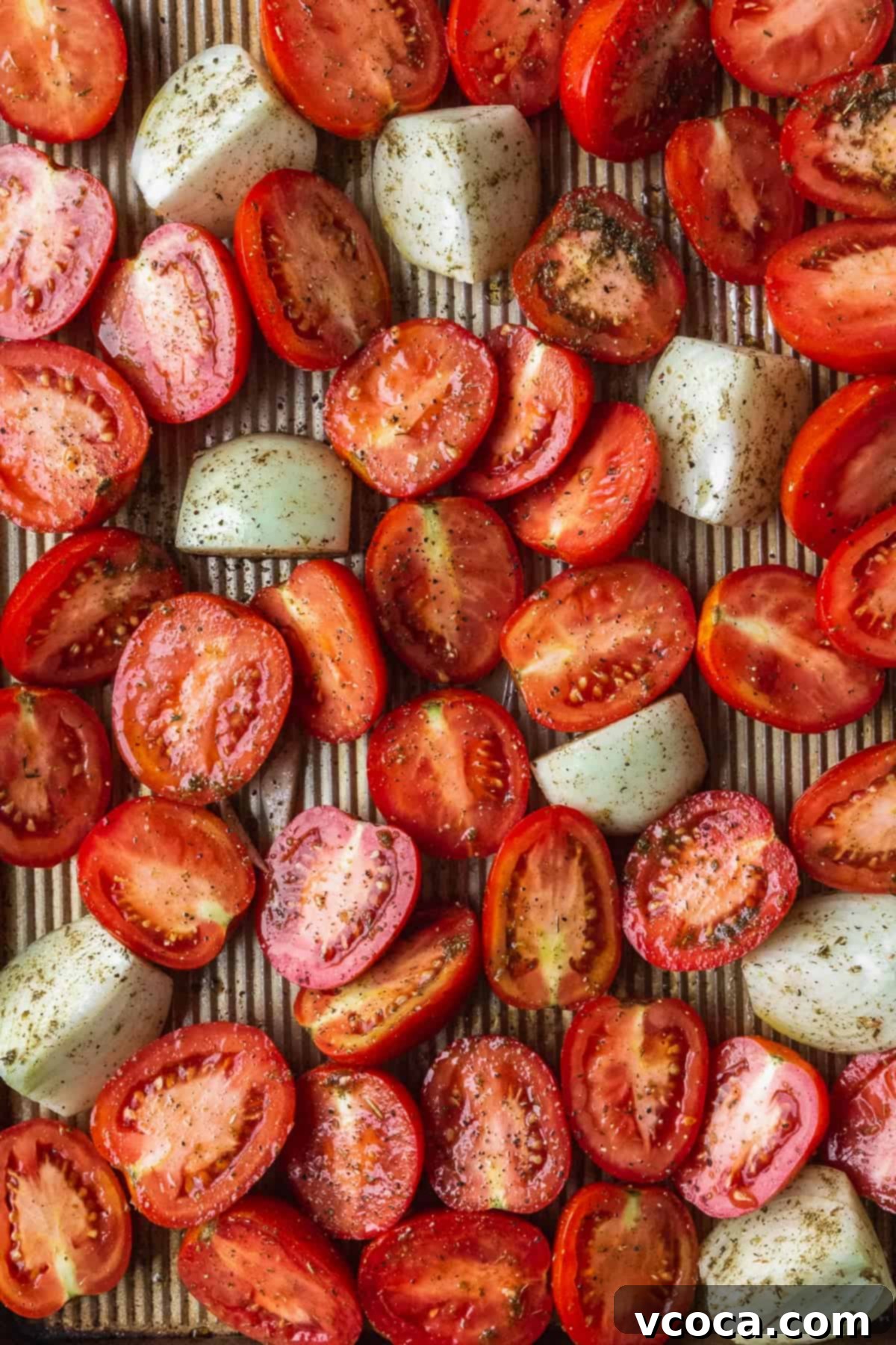 Heartwarming Roasted Tomato Soup 5 Fresh tomatoes sliced in half and quartered onions evenly spread on a baking sheet, seasoned and ready for roasting.