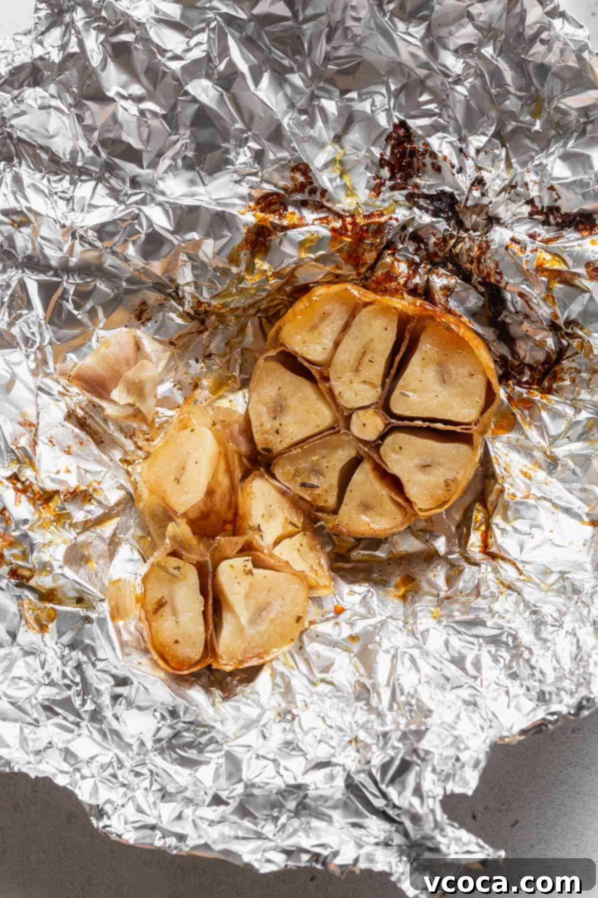 Heartwarming Roasted Tomato Soup 6 A perfectly roasted bulb of garlic, tender and golden, on a piece of aluminum foil after baking.
