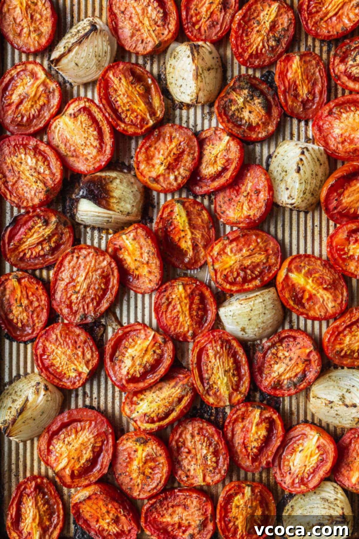 Heartwarming Roasted Tomato Soup 7 A baking tray filled with perfectly roasted and slightly charred tomatoes and onions, glistening with olive oil.