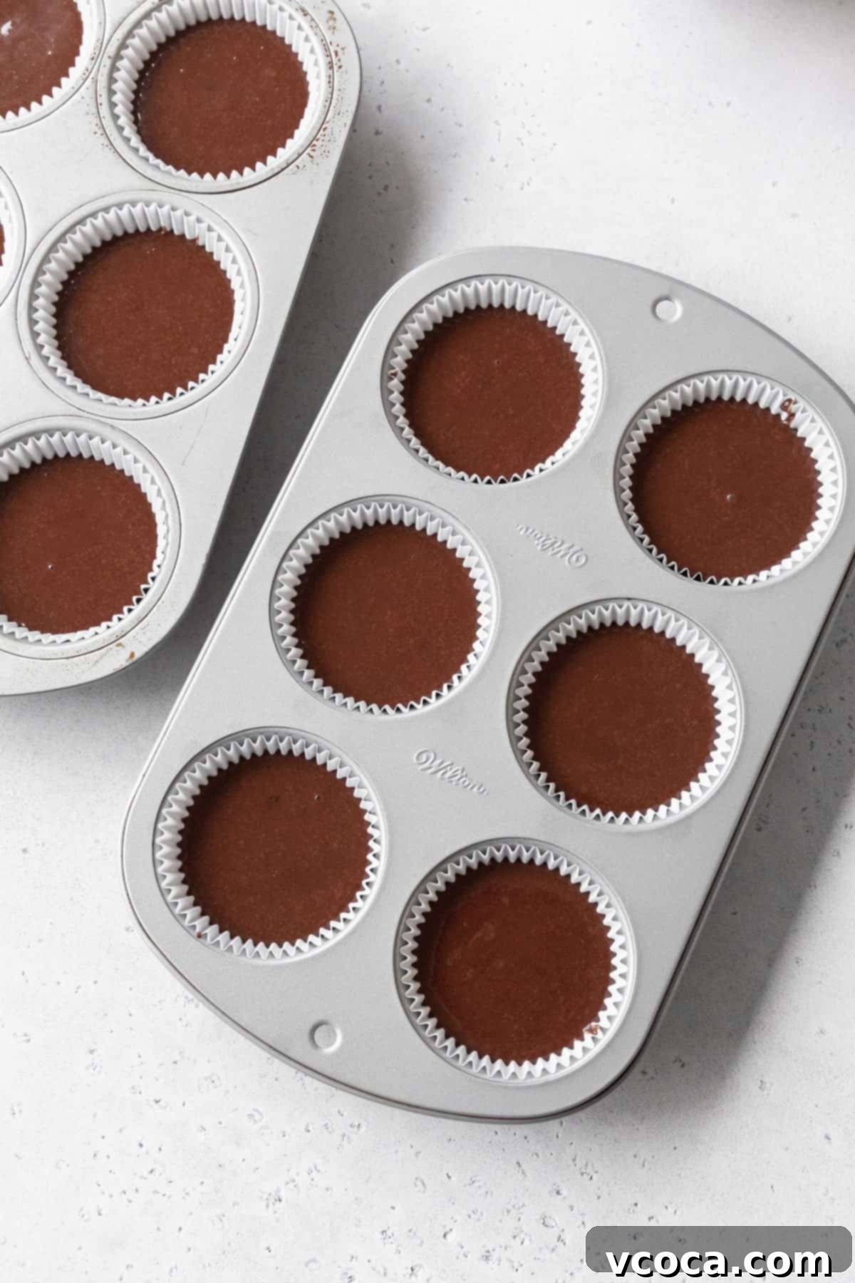 Velvety Chocolate Cupcakes 11 Muffin pans with chocolate cupcake batter inside.