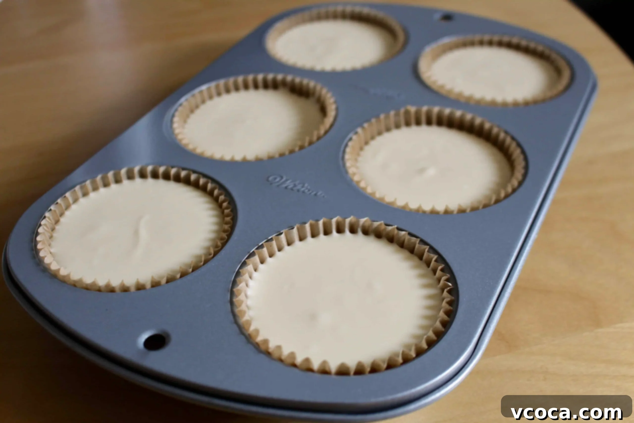 Yuzu Cheesecake Japanese Fusion 5 Individual cheesecake batter neatly scooped into muffin pan liners, ready for baking.