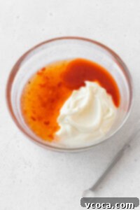 Mayonnaise, sweet chili sauce, sriracha, and rice vinegar in a glass bowl, ready to be mixed for Bang Bang Sauce.