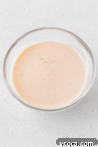 Creamy Bang Bang shrimp sauce mixed together in a glass bowl, showcasing its smooth texture.