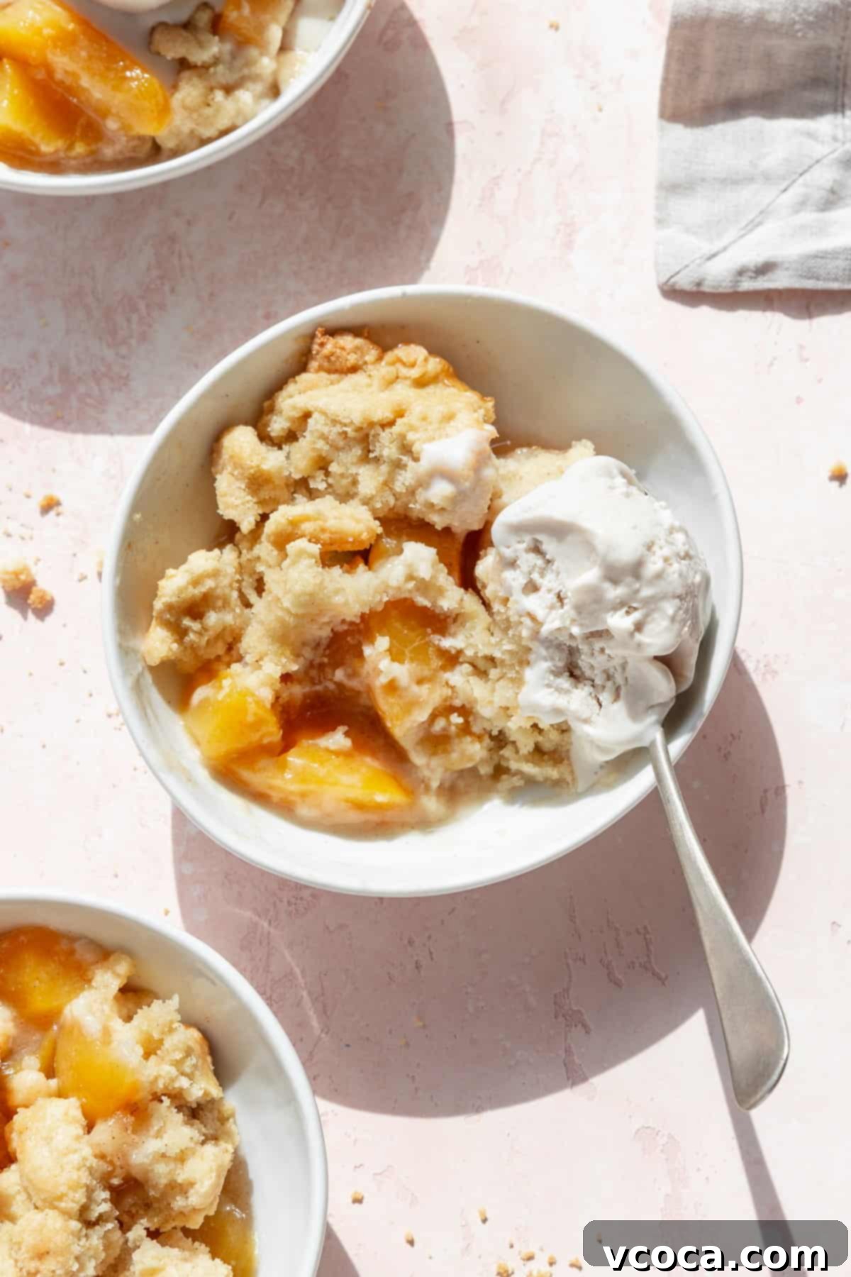 Homemade Peach Cobbler 6 A half eaten bowl of peach cobbler with vanilla ice cream with a spoon in the bowl.