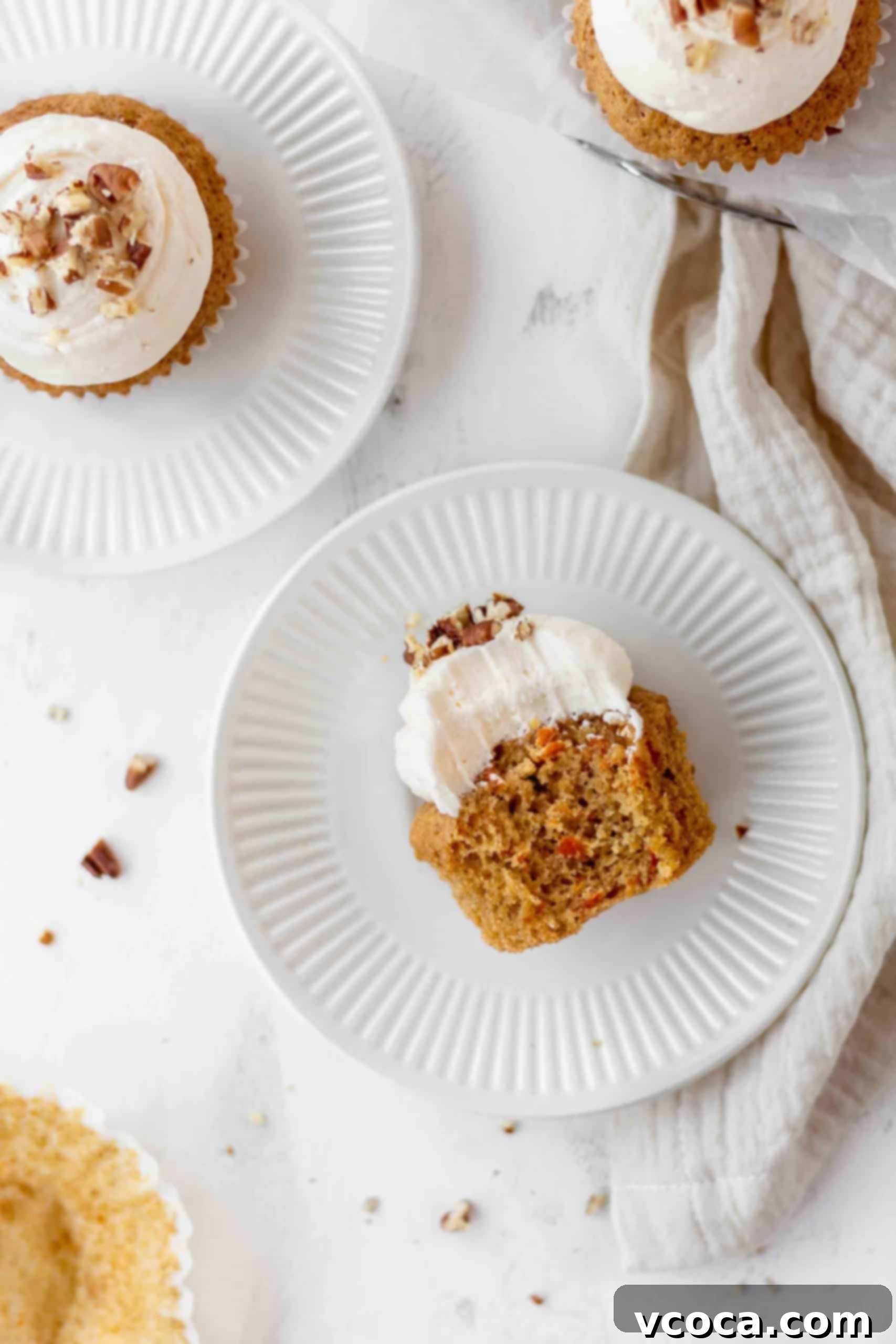 A bitten cupcake with lemon cream cheese frosting on a plate