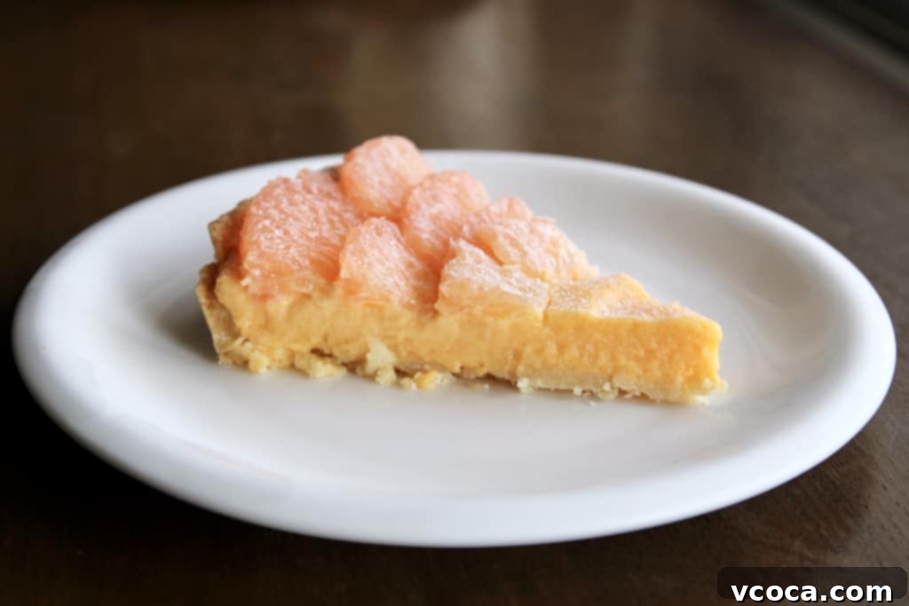 Zesty Grapefruit Tart 2 A beautifully sliced grapefruit curd tart with fresh grapefruit segments on top, revealing the creamy curd and golden crust.