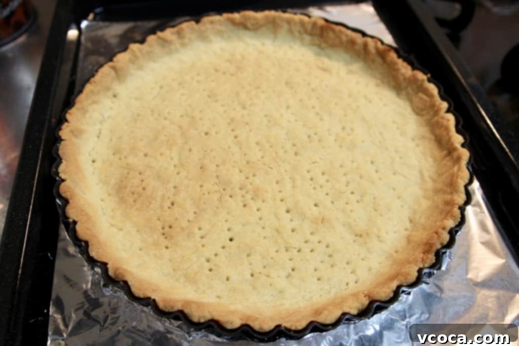 Zesty Grapefruit Tart 3 Tart crust blind baking in a tart pan, golden brown and perfectly crisp.