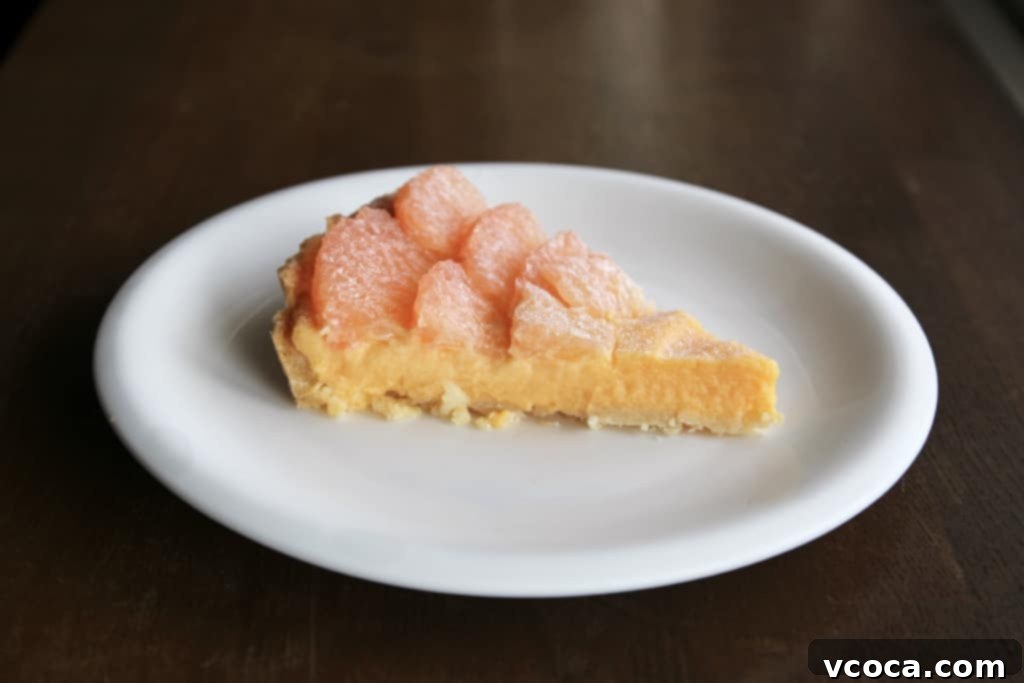 Zesty Grapefruit Tart 7 A close-up of a slice of grapefruit curd tart, showing the creamy curd, crisp crust, and juicy fruit.