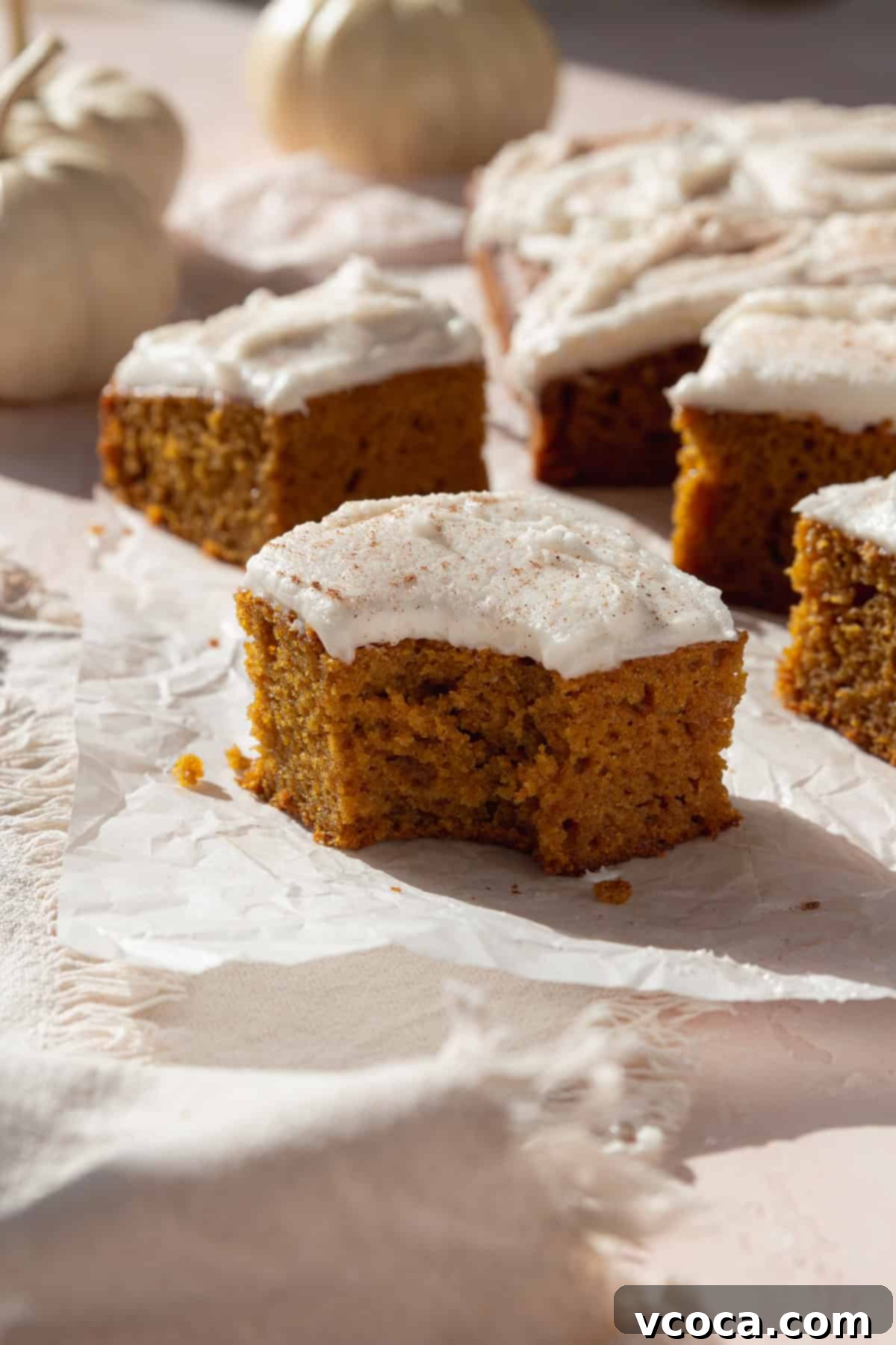 Spiced Pumpkin Squares 13 A delicious bitten pumpkin bar topped with smooth white cream cheese frosting, with more frosted slices ready to serve.