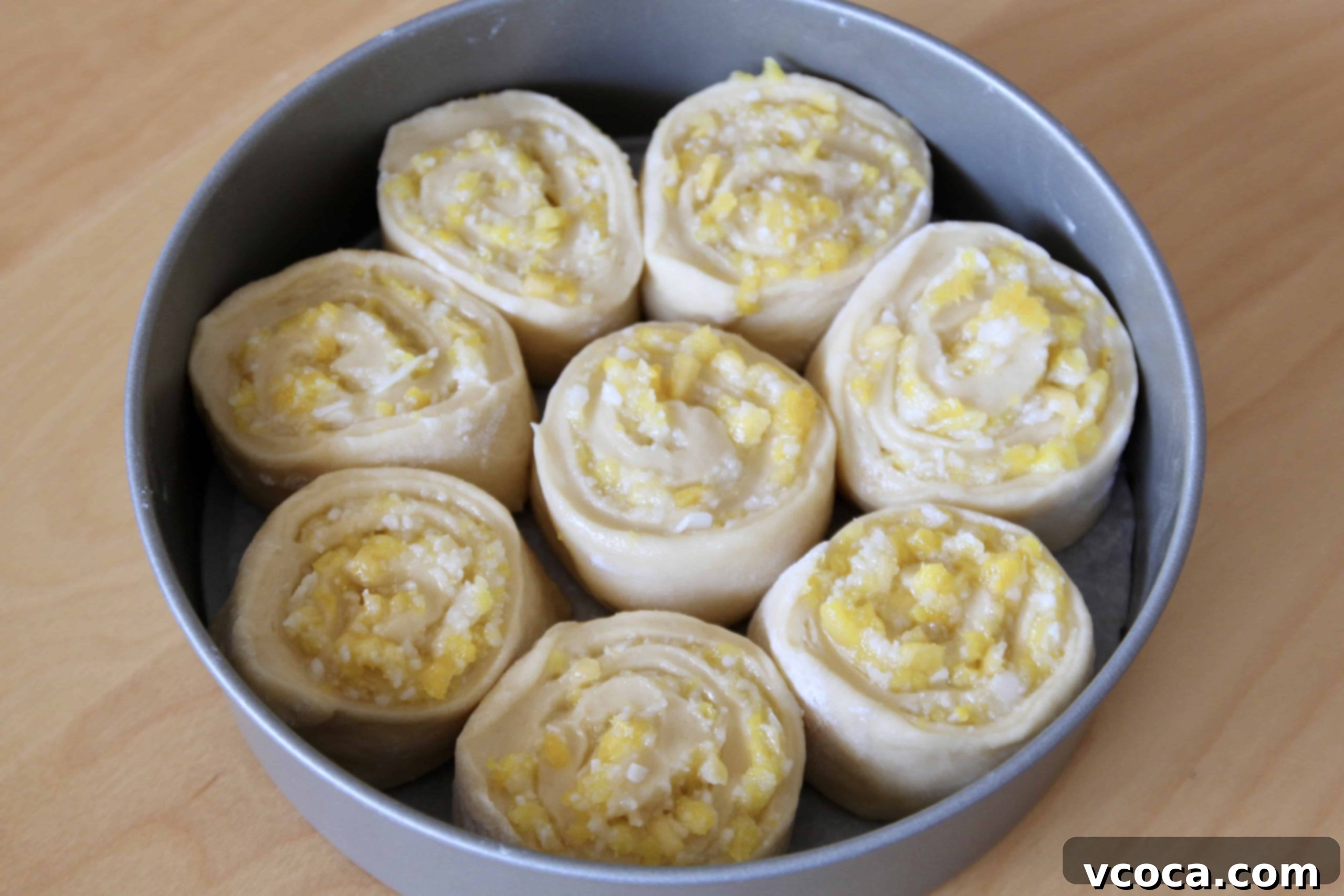 Tropical Piña Colada Swirls 7 Unbaked pineapple and coconut sweet roll dough, arranged in a round cake pan, after the second rise