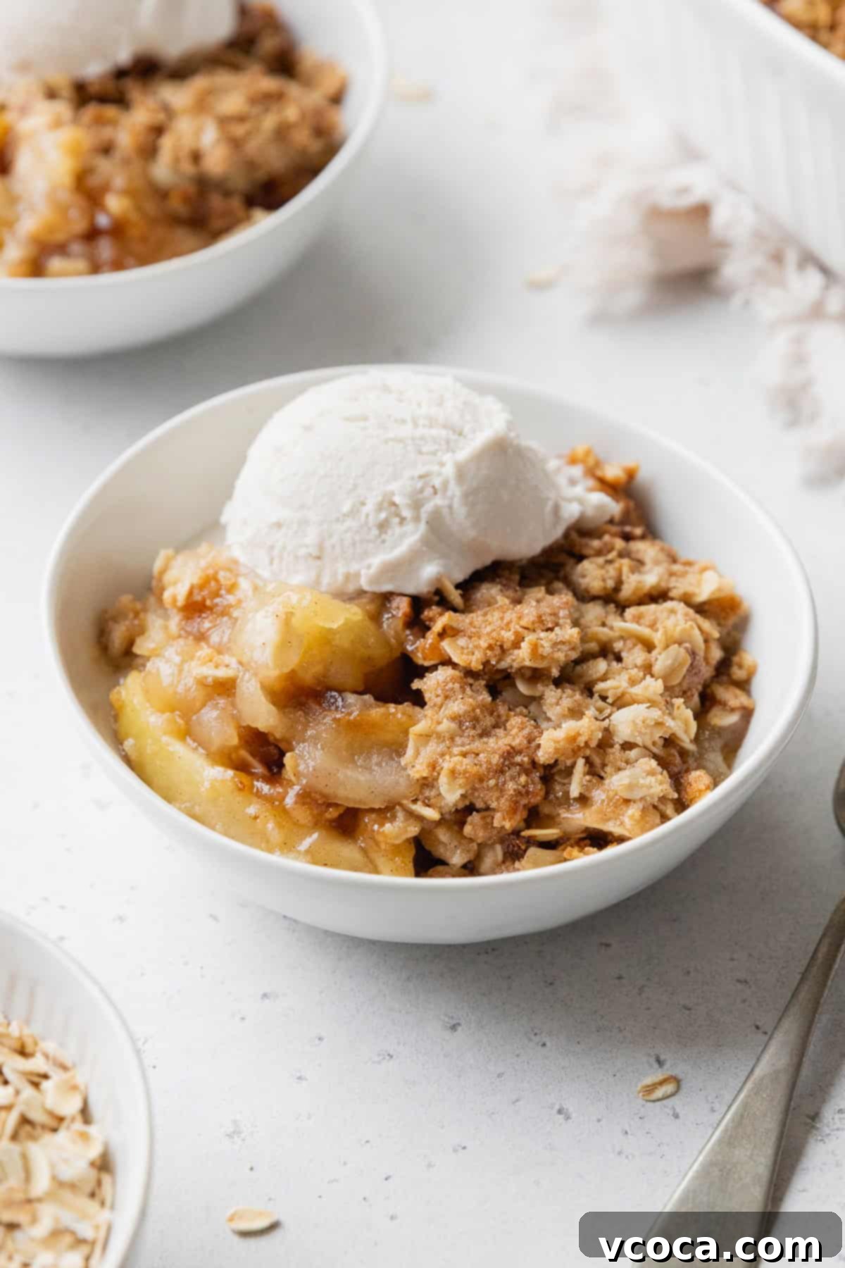Comforting Gluten-Free Apple Crisp 10 Apple crisp in a white bowl with a scoop on vanilla ice cream on top.
